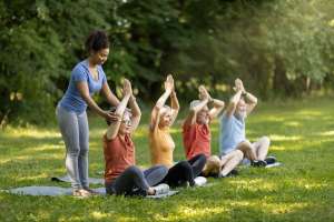 Outdoor Yoga Class. Group of smiling senior people training together outdoors, happy mature men and women in sportrswear sitting in lotus position with hands above head, enjoying healthy lifestyle
