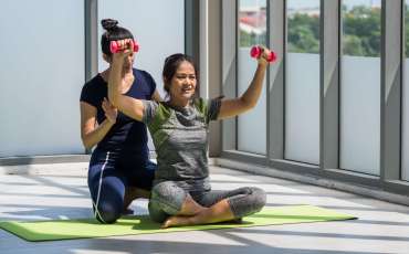 Two asian women doing yoga together at a gym.